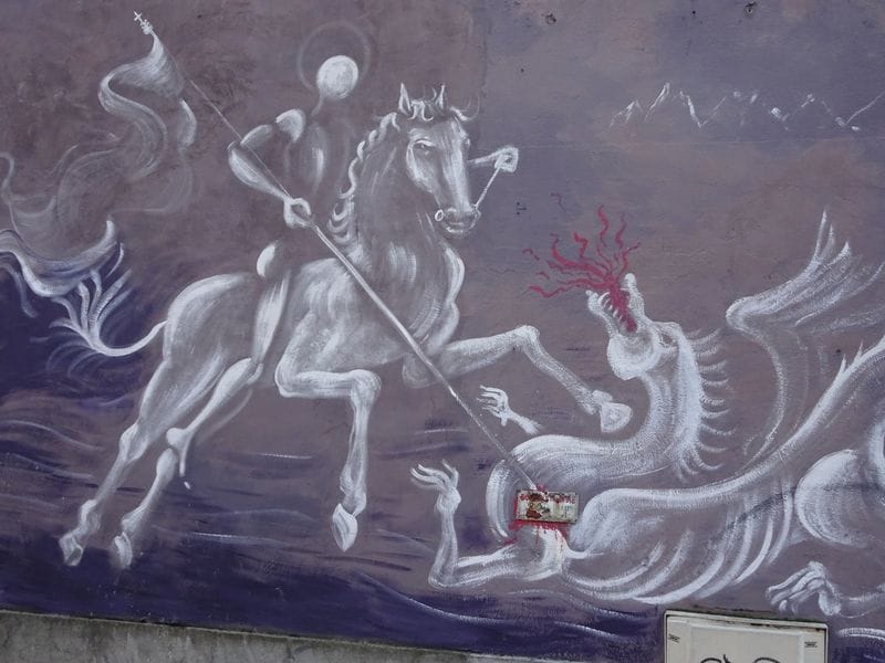 Homme blanc sur un cheval terrassant un dragon avec une lance