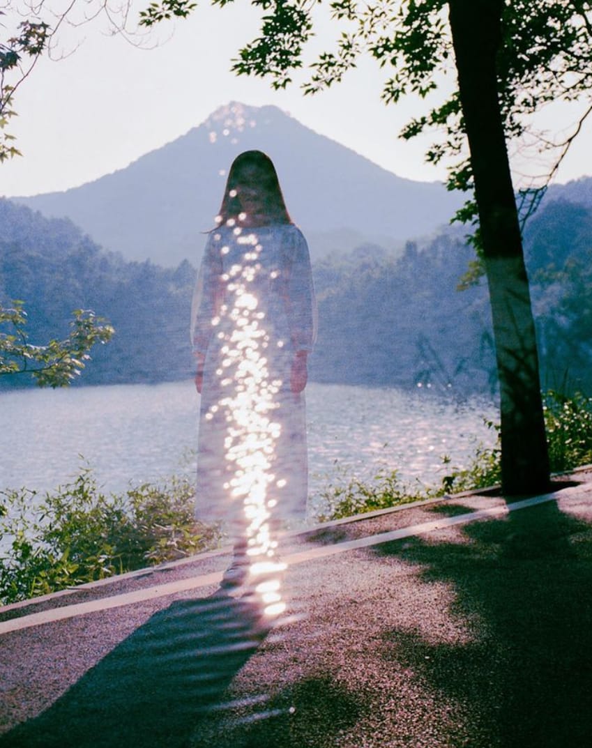 Photographie d'une silhouette féminine sur une route devant un lac par Li Hui